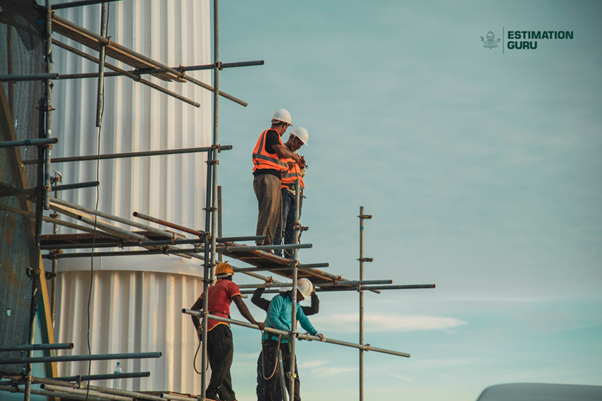 Four construction workers are working on scaffolding